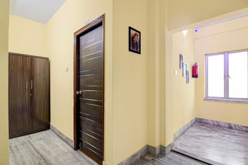 a hallway with a black door and a window at Hotel O White Sapphire in Jādabpur