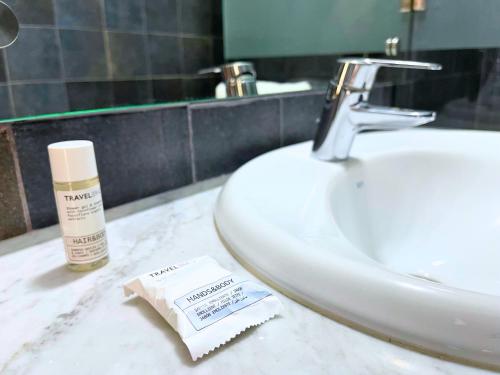 a bathroom counter with a sink and a bottle of moisturizers at Hôtel Olympic in Fez