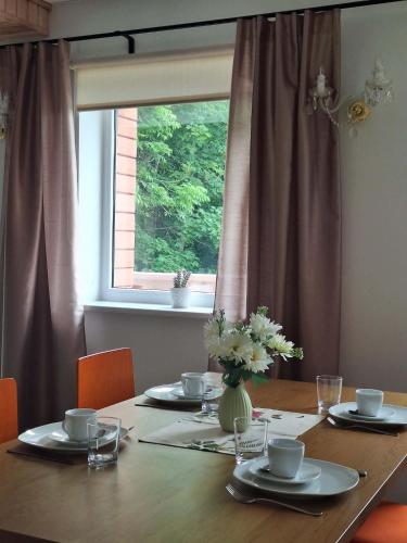 a table with a vase of flowers on it with a window at Konrad Guesthouse in Kuressaare