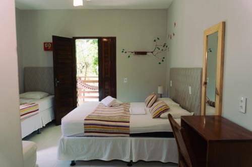 a bedroom with a bed with a desk and a window at Pousada Munguba in Jericoacoara
