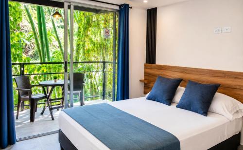 a bedroom with a bed and a balcony with a table at Carriqui Garden Hotel in Pereira