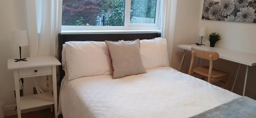 a bedroom with a bed with white sheets and a window at Eltham Gem in Eltham