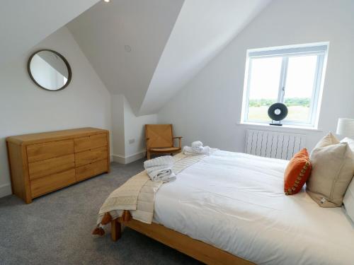 a bedroom with a bed and a dresser and a window at Glynllifon 9 in Llanallgo