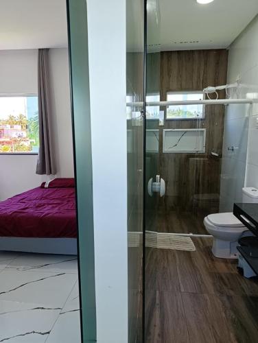 a bathroom with a shower and a toilet and a bed at Pousada Natural Hostel in Maragogi