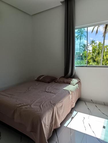 a bed in a room with a window at Pousada Natural Hostel in Maragogi