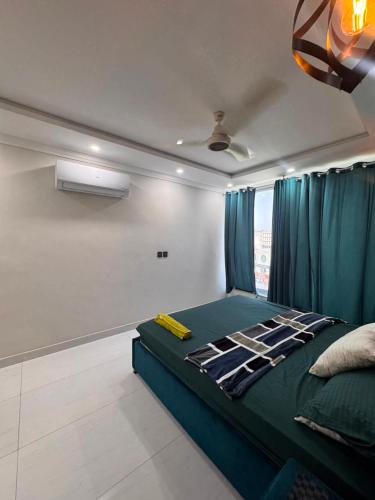a bedroom with a green bed with blue curtains at Shazi Heights in Lahore