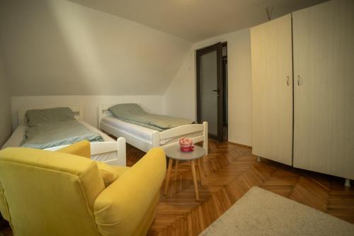 a living room with two beds and a yellow chair at Vikendica Mir Čortanovci in Čortanovci