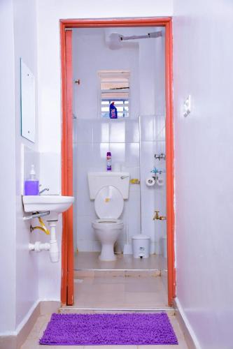 a white bathroom with a toilet and a sink at Homes By Vee in Eldoret