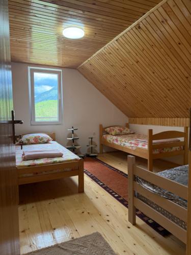 a attic room with two beds and a window at DreamHouse Grebaje in Gusinje