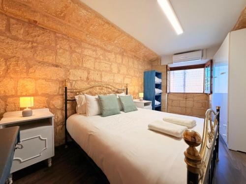 a bedroom with a bed and a stone wall at Charming 450-Year-Old House with Pool in Naxxar in Naxxar