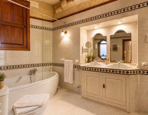 a bathroom with a tub and two sinks and a bath tub at Charming 450-Year-Old House with Pool in Naxxar in Naxxar