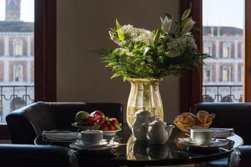 a vase with flowers and fruit on a table at Locanda Leon Bianco on the Grand Canal in Venice