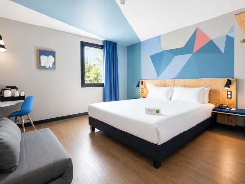 a bedroom with a bed and a desk and a couch at Ibis Styles Evry Lisses Paris Sud in Courcouronnes