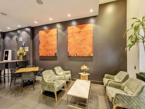 a waiting room with chairs and a table and a piano at ibis Sydney World Square in Sydney