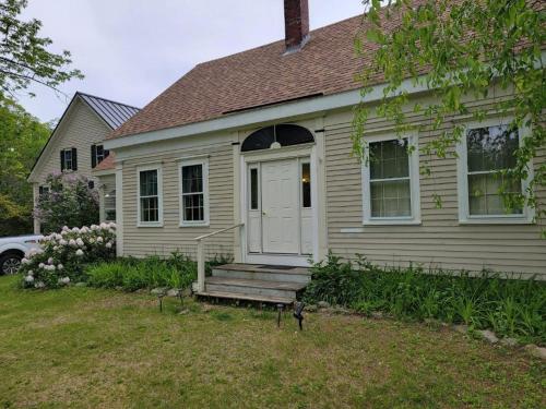 a house with a porch with a bench in the yard at Hawks House Inn in Walpole