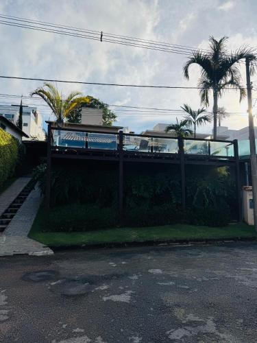 a fence in front of a house with palm trees at Casa Brisa Escarpas in Capitólio