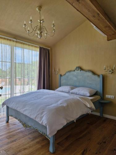 a bedroom with a blue bed and a chandelier at Seventh Heaven Village Glamping in Rogašovci