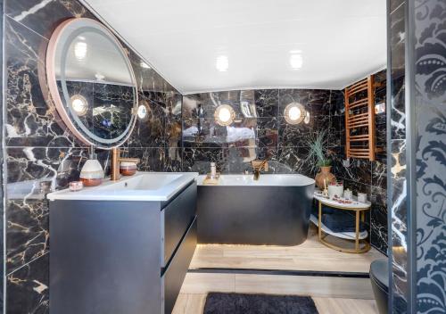 a bathroom with a tub and a sink and a mirror at Love Room sur l'eau & Rooftop in Asnières-sur-Seine