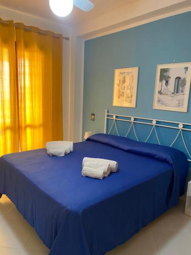 a bedroom with a blue bed with towels on it at Sole Mare da Tina in Cittadella del Capo
