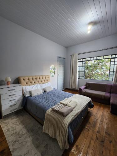 a bedroom with a large bed and a couch at Quarto no coracao da cidade entre batel, merces e centro Excelente localizacao in Curitiba