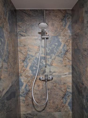 a shower in a bathroom with a stone wall at Srub v lese in Hrabŭvka