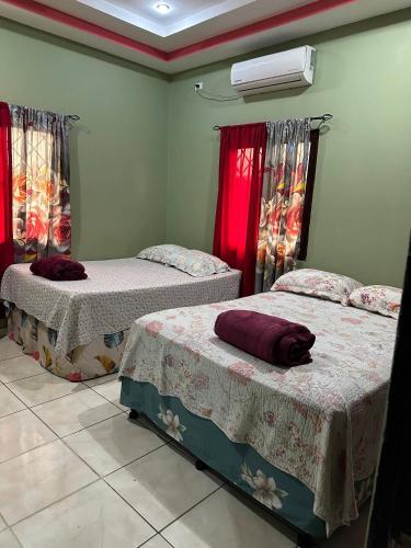 two beds in a room with red curtains at Casa Playa Cieneguita in Puerto Cortés