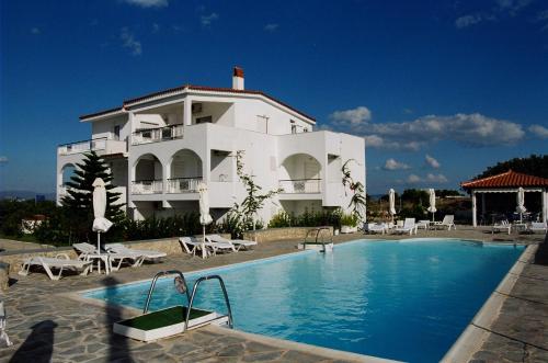 a large white building with a swimming pool in front of it at Long View Apartments in Porto Heli