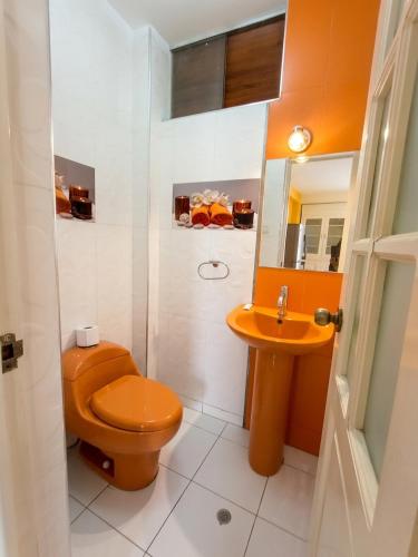 a bathroom with an orange toilet and a sink at Hospedaje & Minidepas VALERY in Trujillo
