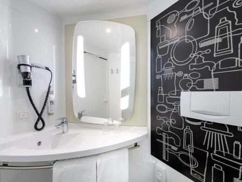 a bathroom with a sink and a mirror at Ibis Münster City in Münster
