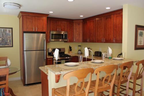 a kitchen with wooden cabinets and a kitchen island with chairs at The Beach Palms Carlsbad in Carlsbad