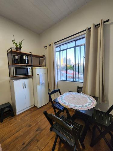 a living room with a table and chairs and a kitchen at Quarto central em ótima localização in Curitiba