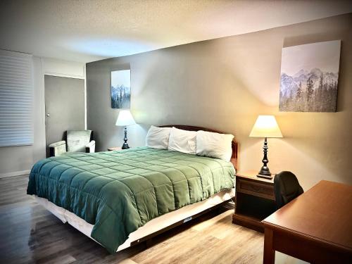 a bedroom with a bed and a desk and two lamps at APM Inn & Suites in Martinsburg