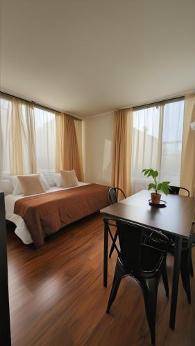 a bedroom with a bed and a table and windows at Personal Aparts Bellas Artes in Santiago
