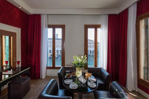 a living room with red curtains and a table and chairs at Locanda Leon Bianco on the Grand Canal in Venice