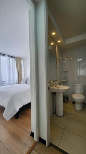 a bedroom with a bed and a sink and a toilet at Apartments Bellas Artes in Santiago