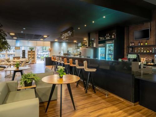 a restaurant with a bar with chairs and tables at ibis Piracicaba in Piracicaba