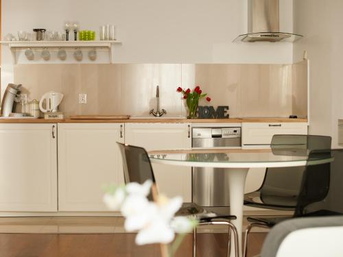una cocina blanca con mesa y algunas sillas en Apartament Witawa 22, en Gdynia