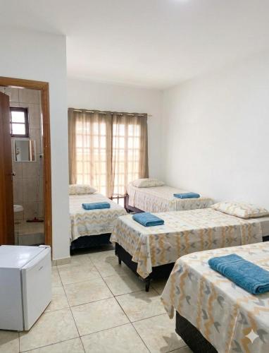 a room with three beds and a bathroom at Pousada Alphaville in Aparecida
