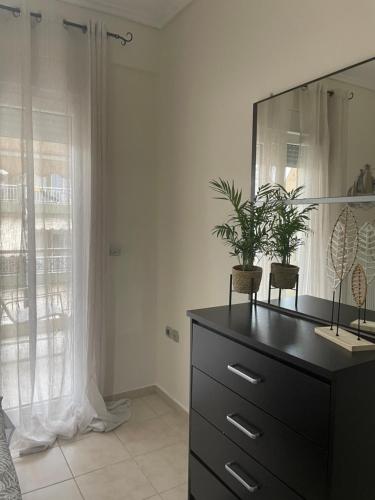 a dresser with a mirror and plants on top of it at Sea And Sand Apartment in Nea Kallikrateia