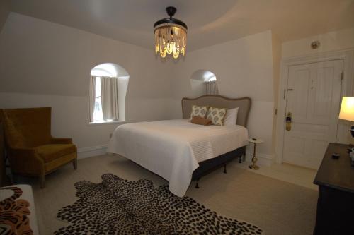 a bedroom with a bed and a chair and a chandelier at Garfield Inn in Port Austin