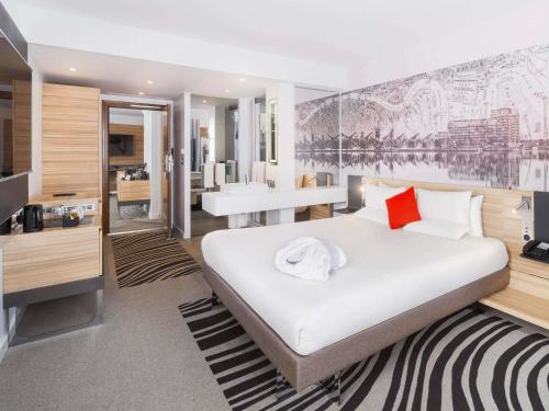 a bedroom with a large bed and a bathroom at Novotel London Excel in London