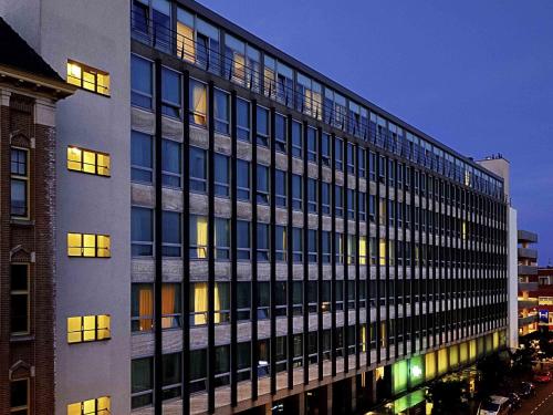 a tall building with many windows at night at Ibis Den Haag City Center in The Hague