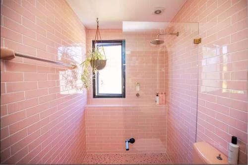a pink bathroom with a shower and a sink at The Royale Bundeena in Bundeena