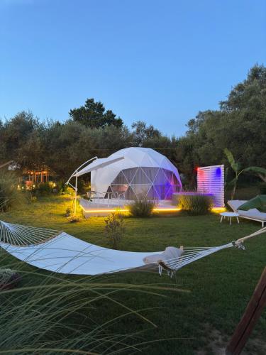 a person laying on a hammock in a field with a tent at La Fontana Glamping in Caria