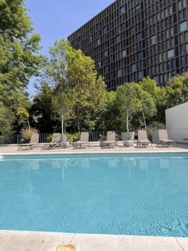 a large swimming pool with chairs and a building at Visa Trip Cozy Stay in Guadalajara