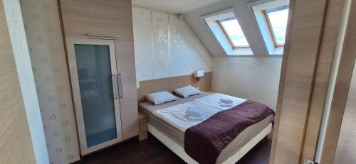 a small bedroom with a bed and two windows at T8 Sunset Tihany 19 in Tihany