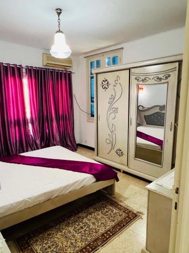 a bedroom with a large bed with purple curtains at maison hajji in Mezraya