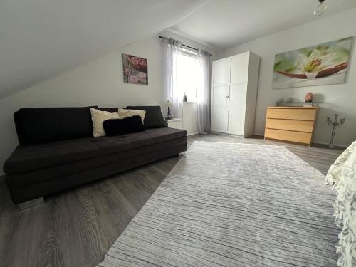 a living room with a black couch and a rug at Ferienwohnung Emerson in Edemissen