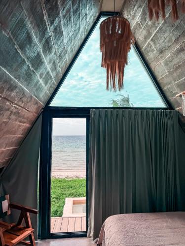a bedroom with a large window with a view of the ocean at Danselis Boutique Hotels in Telchac Puerto