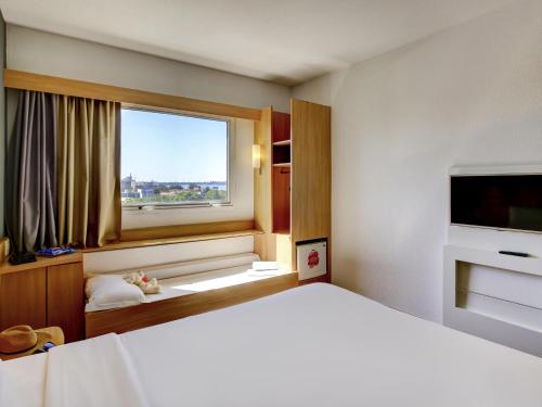 a bedroom with a large bed and a window at ibis Vitoria Praia do Canto in Vitória